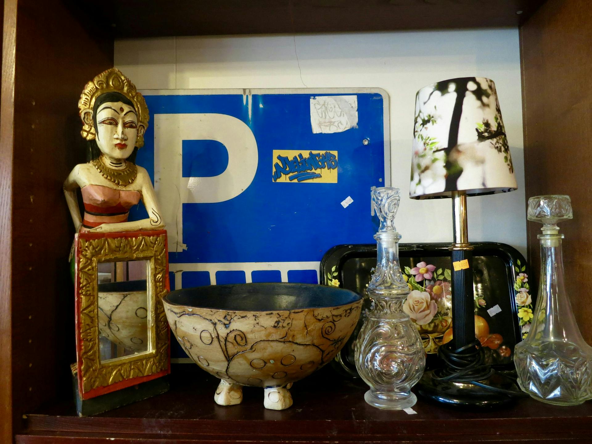 Random objects and a parking traffic sign on display at a thrift store. 