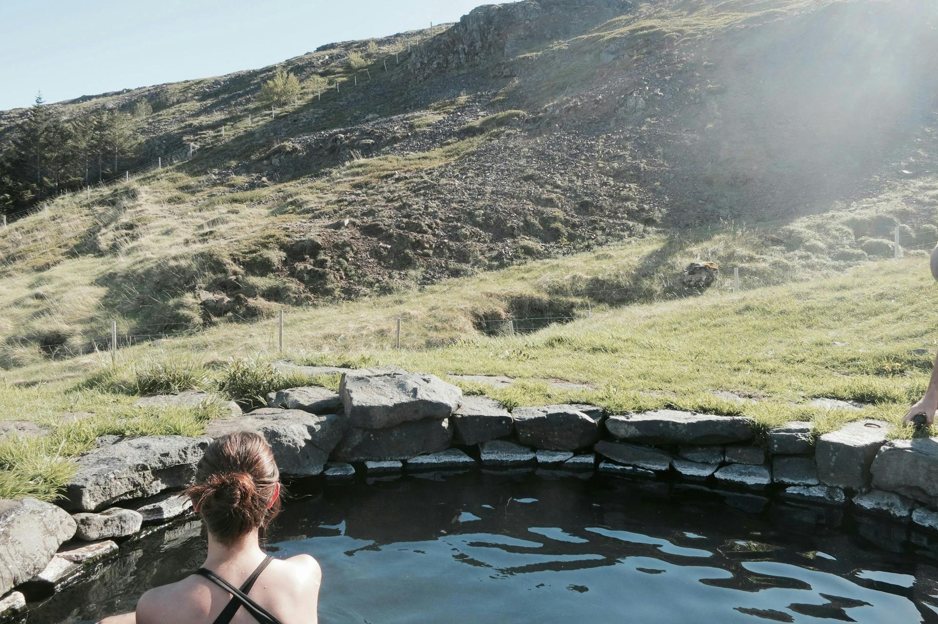 A woman bathing in a geothermal pool. Sun is shining. 