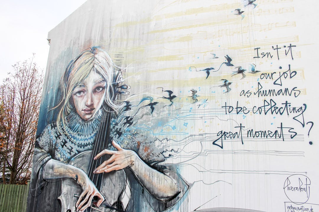A big mural of an ugly girl playing the cello while birds fly away from her instrument. A caption saying something about life and humanity.