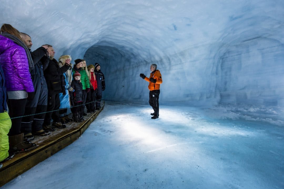 A guide talking to a group of visitors inside a glacial cave. 