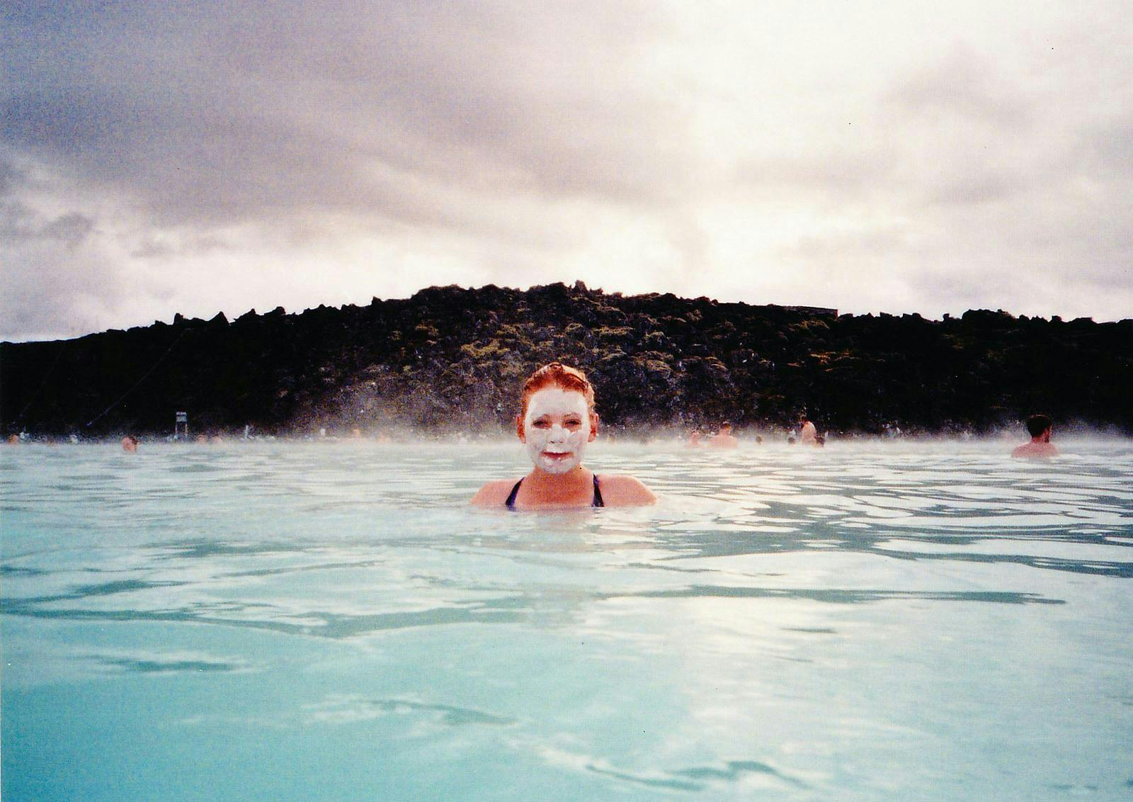 A woman covered in white silica mud relaxing in the Blue Lagoon. 