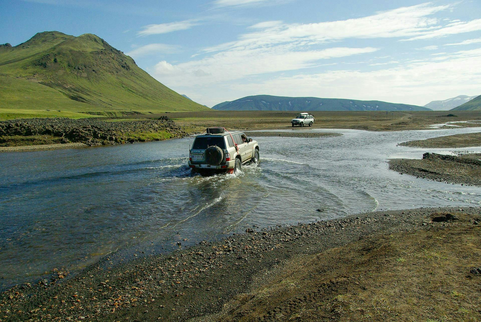 4x4s crossing a river in the highlands