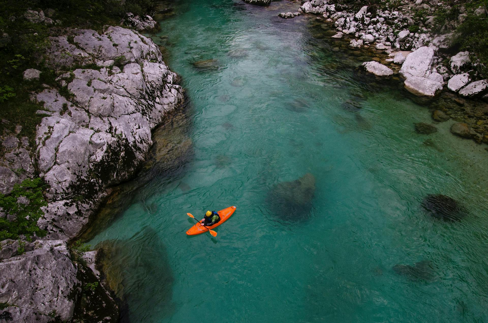 An aerial view of a man kayaking on a large river. 