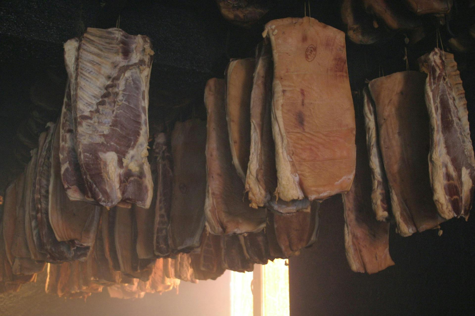Uncut prsut ham hanging from the ceiling. 