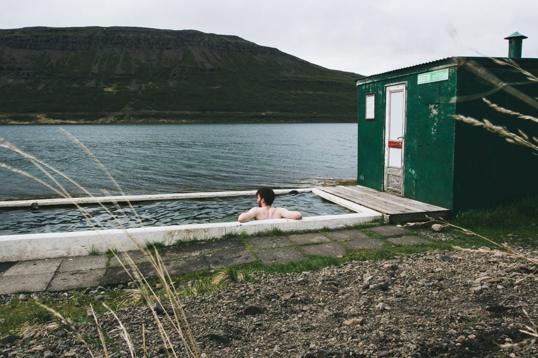 A man relaxing at a small man-made pool by the ocean, Iceland. 