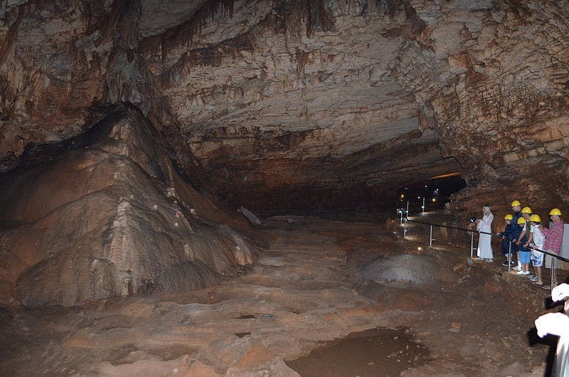 People standing inside the Vjetrenica Cave with helmets for protection