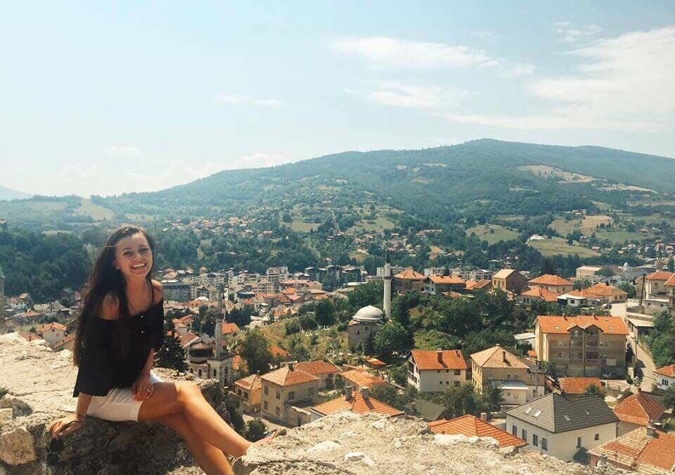 A girl smiling with the view over Travnik behind her. 