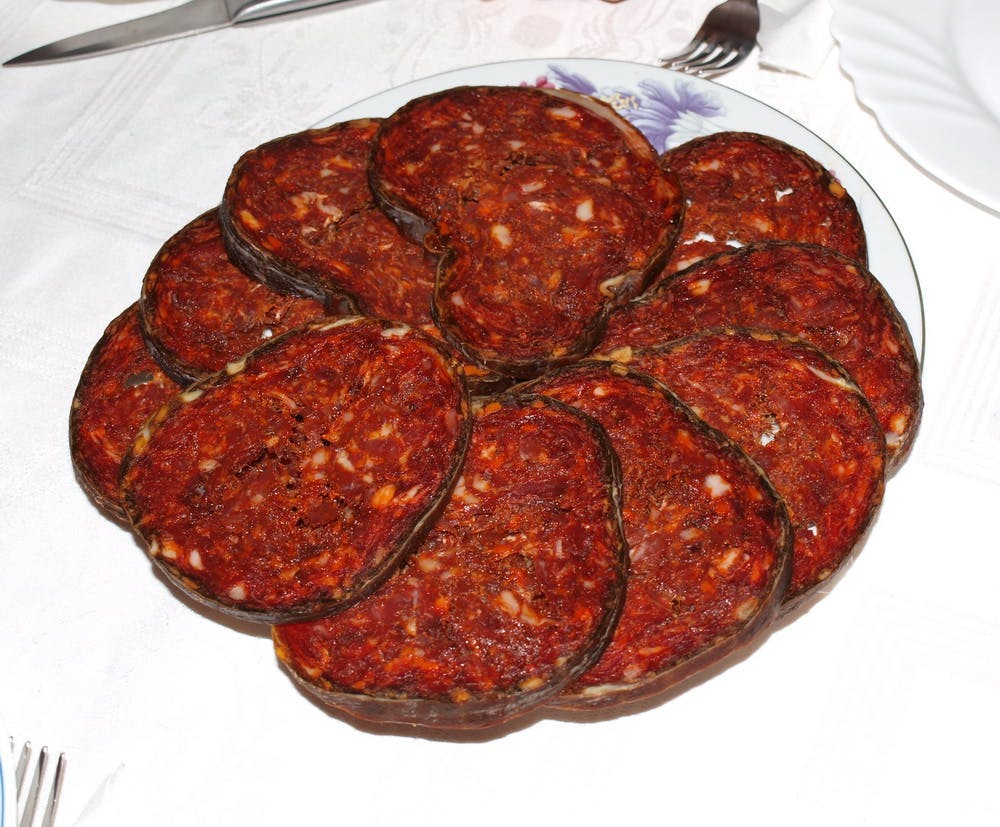 Spicy Kulen sausage, sliced up and placed on a plate. 