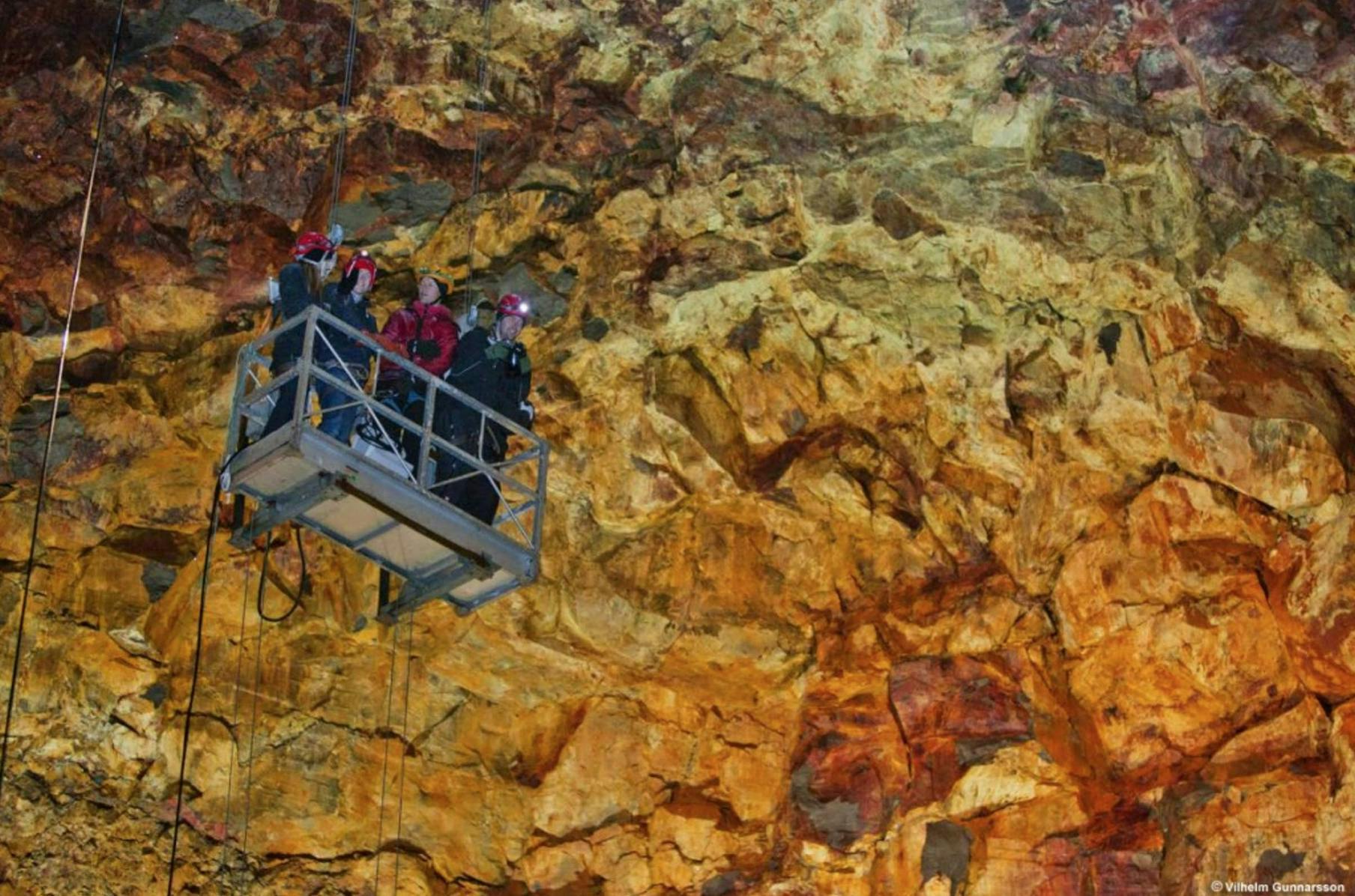 A group of people in a cable car inside a volcano. 