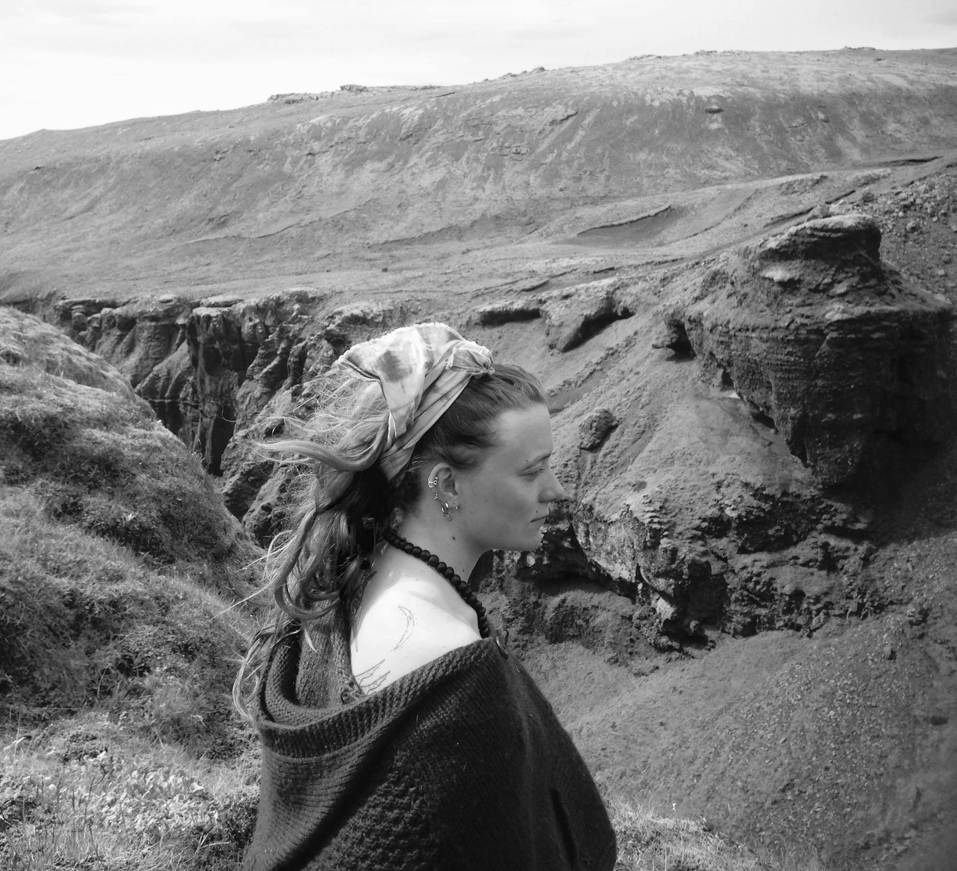 A black and white photo of a woman hiker with mountains in the background. 
