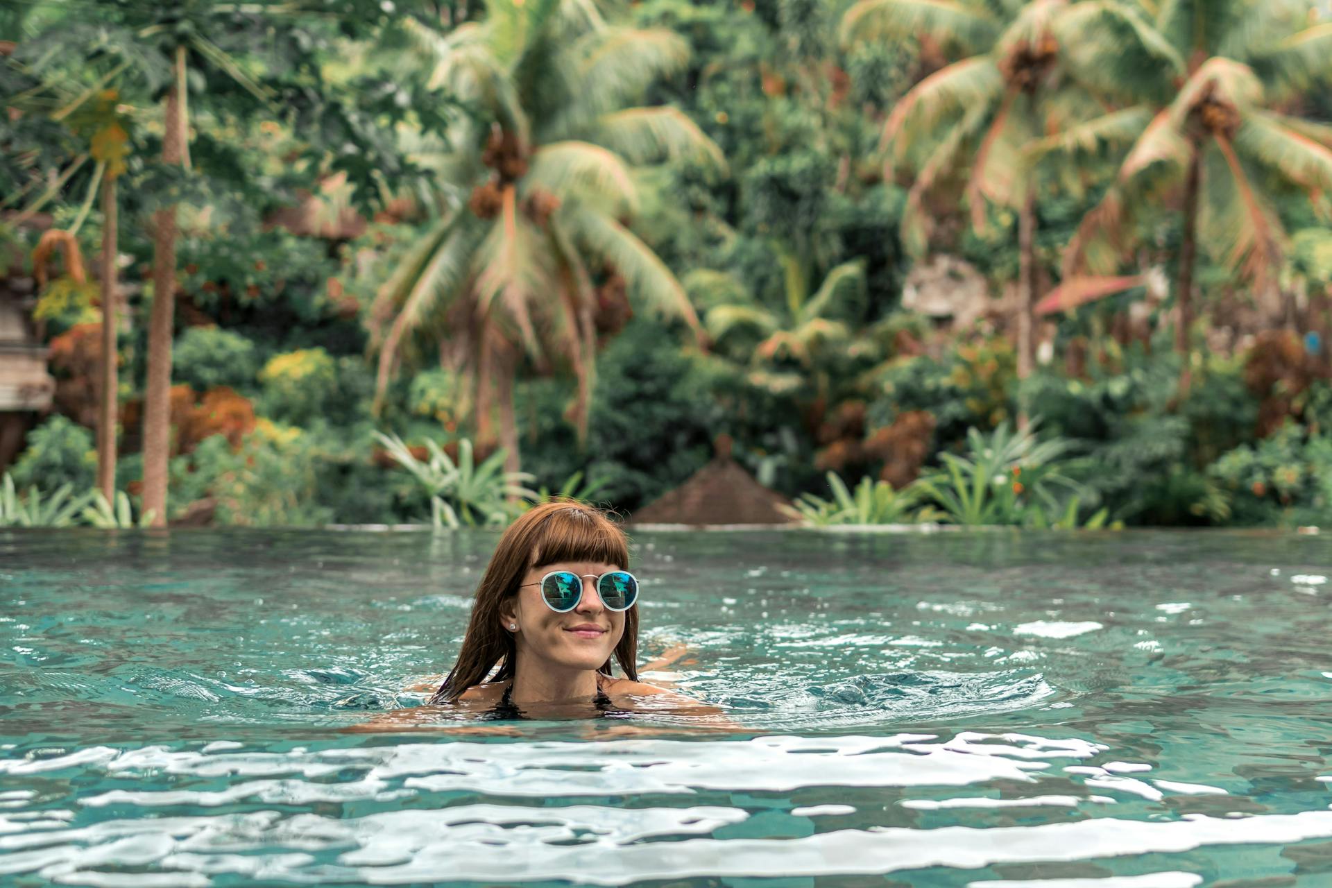 A woman with sunglasses swimming in a lake in Bali. 