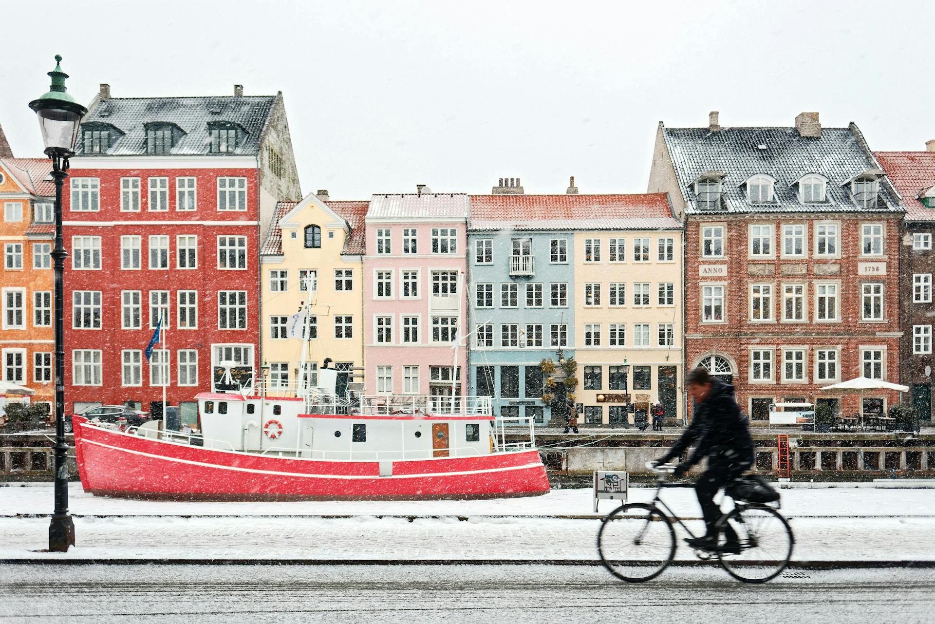 A man on a bike on a snowy day in Nyhavn, Copenhagen. 