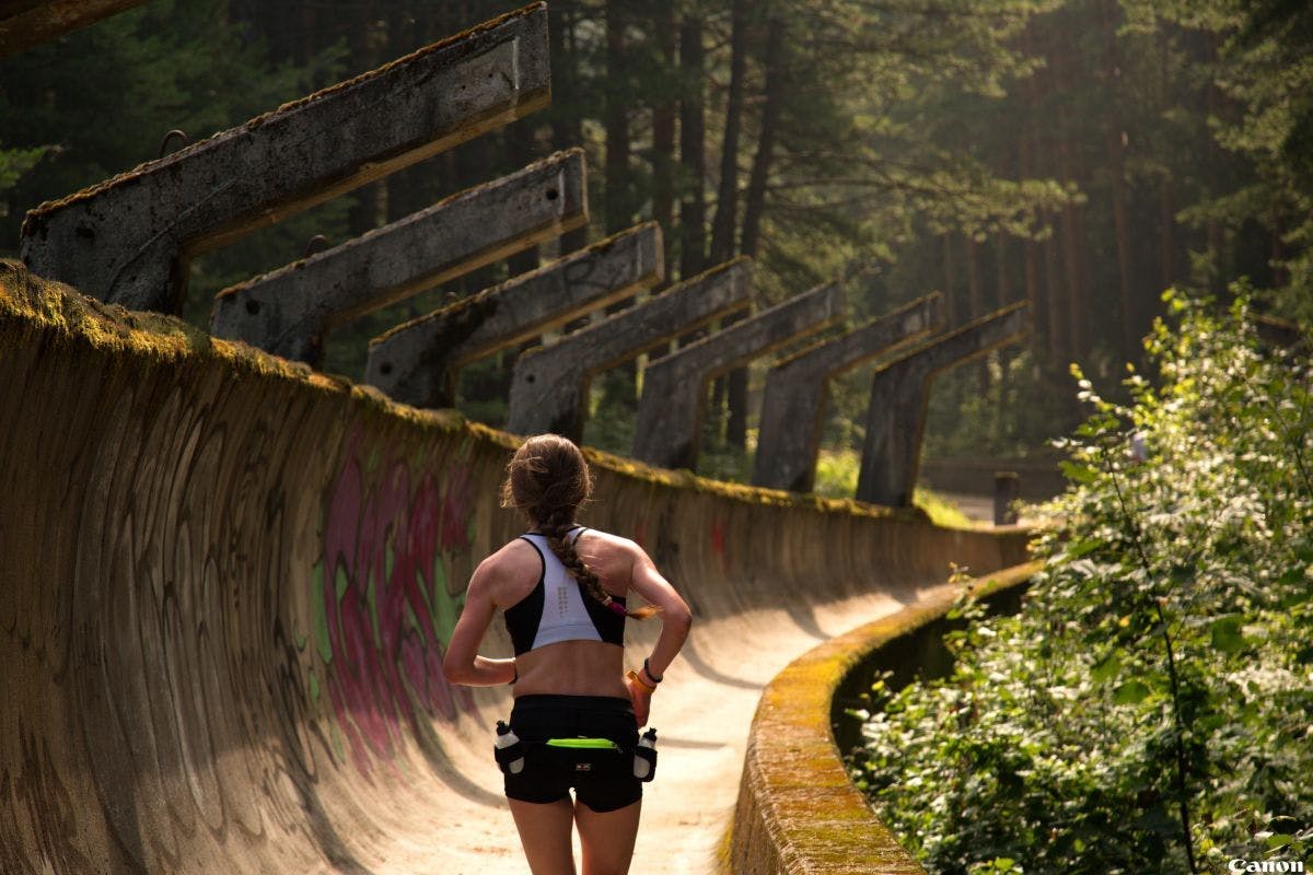 A woman running down bobsleigh track on Mount Trebevic.
