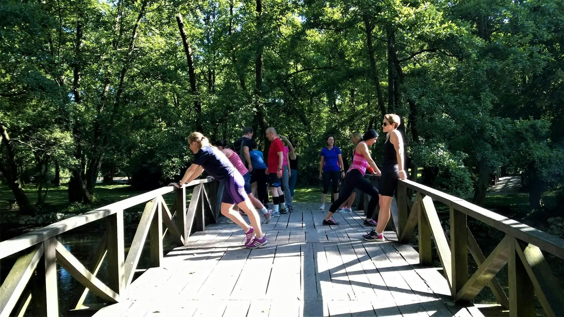Runners stretch on a wooden bridge. 