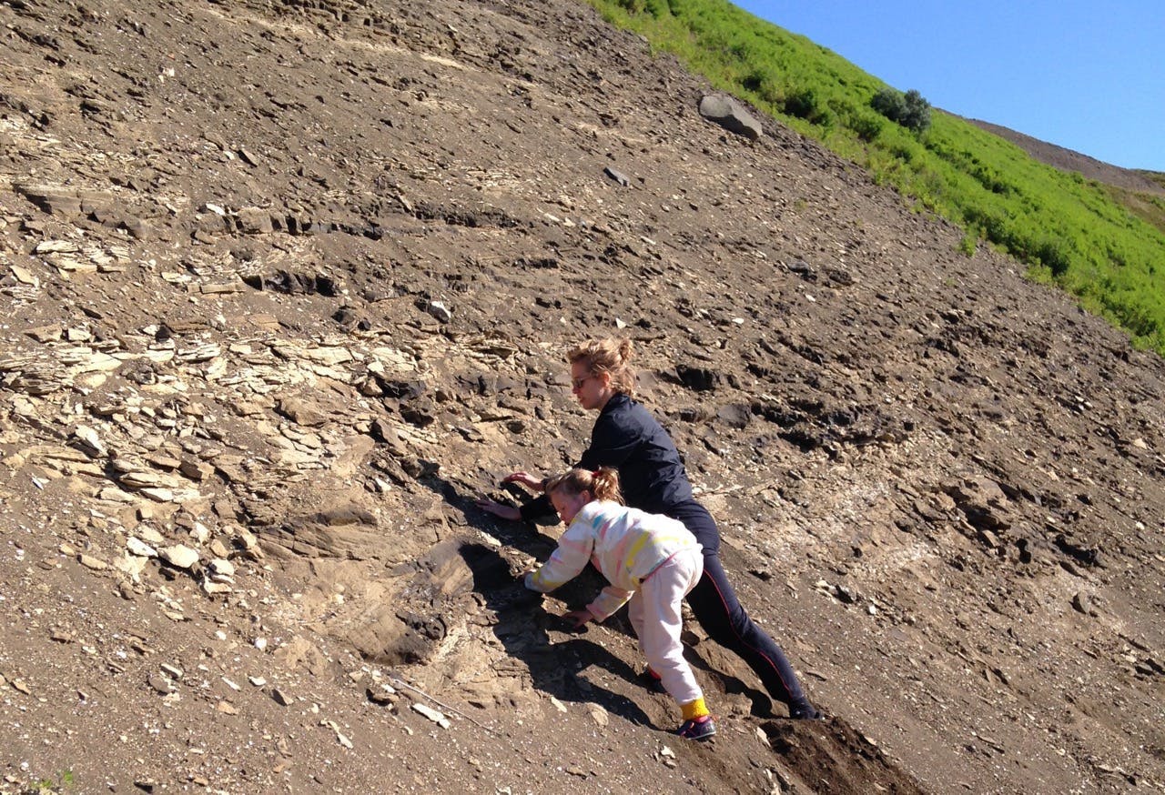 A woman and a child climbing a hill of fossils. 