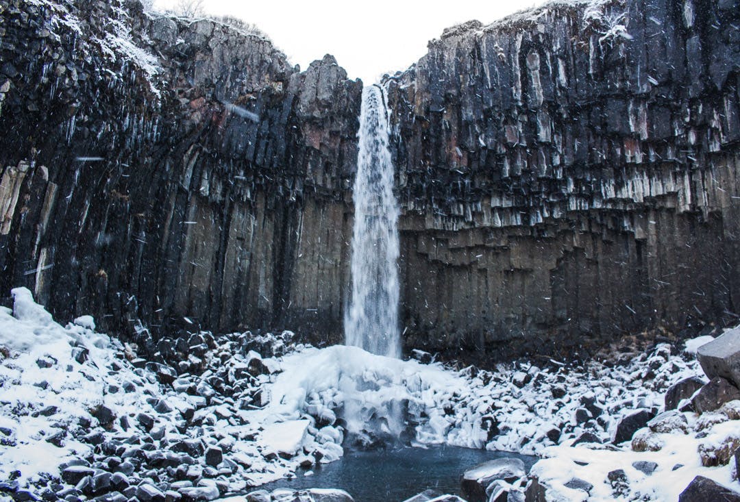 Svartifoss waterfall, surrounded by basalt columns and snow. Skaftafell National Park, Iceland.